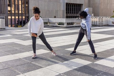 African american women stretching on urban rooftop plaza in hoodies morning fitness duo