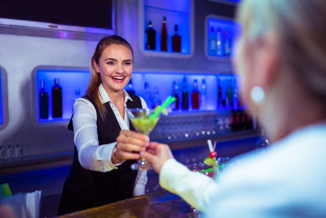 Beautiful bartender serving cocktail to woman in nightclub