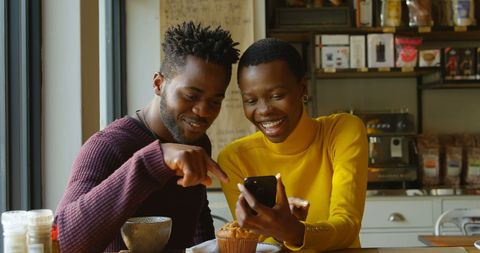 Young Couple Sharing Joyful Moment with Smartphone at Cafe