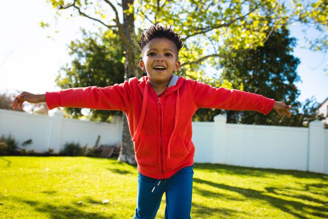 Portrait of happy african american boy widening arms in backyard. Spending quality time at home, domestic life and childhood concept.