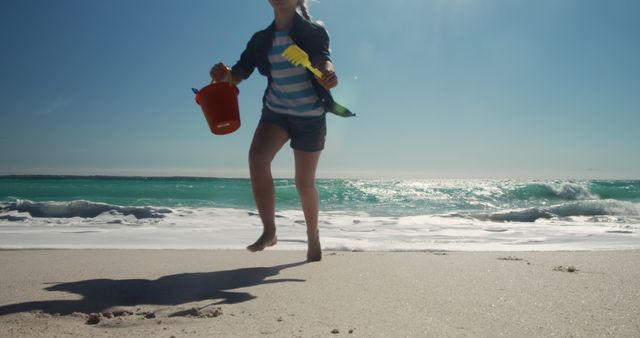 Child playing on beach with red bucket and toy shovel on a sunny day - Download Free Stock Images Pikwizard.com