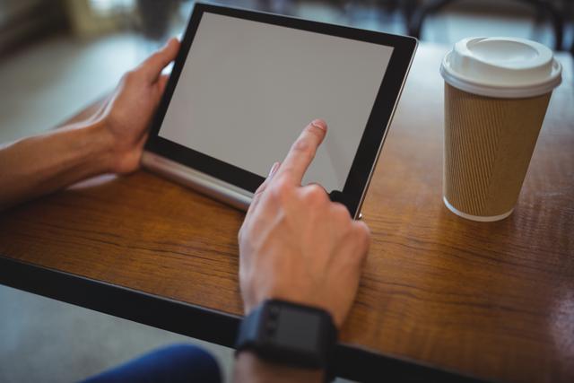 Man interacting with digital tablet while having coffee in a cafe. Perfect for themes involving technology, casual lifestyle, remote work, digital interaction, and modern living. Ideal for use in website headers, blog posts, advertisements, and social media content related to technology and coffee culture.