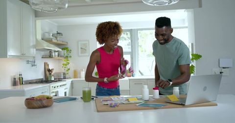African american couple organizing supplements and planning wellness at sunlit kitchen island