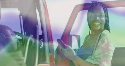 Joyful Black Woman with Smartphone by Red SUV Door in Outdoor Adventure