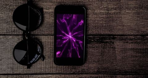 Smartphone with abstract purple light design display on wooden desk