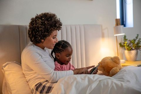 Mother with daughter bonding using smartphone in cozy bedroom