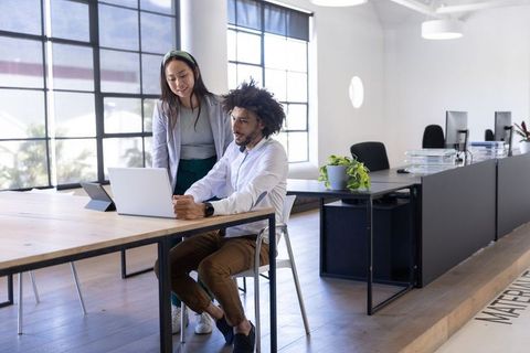 Diverse Coworkers Collaborating in Modern Office with Laptop
