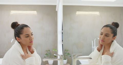 Woman Reflecting in Bathroom Mirror Holding Neck