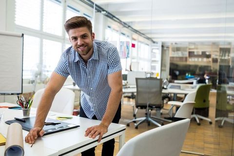 Male Professional Reviewing Blueprint in Modern Office