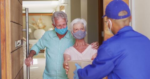 Senior Couple Receiving Package from Delivery Man During Pandemic