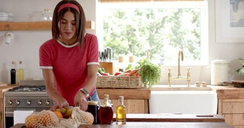 Woman organizing fresh ingredients in rustic farmhouse kitchen