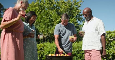 Mixed Group Friends Barbecuing Vegetables in Lush Garden Setting