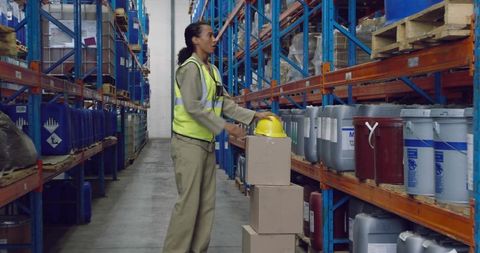 Warehouse Worker Arranging Boxes Amidst Industrial Hazard Drums