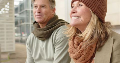 Senior couple enjoying urban getaway, smiling woman in knit hat and cozy scarves