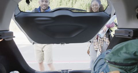 Smiling couple opening car trunk for camping adventure