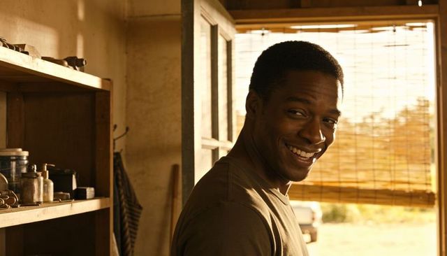 Smiling african american man standing in rustic garage workshop with warm golden light