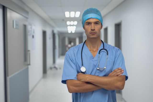 Portrait of male surgeon standing with arms crossed in the corridor at hospital