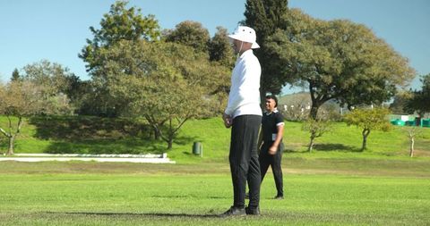 Cricket Players and Umpire Engaging in Outdoor Match