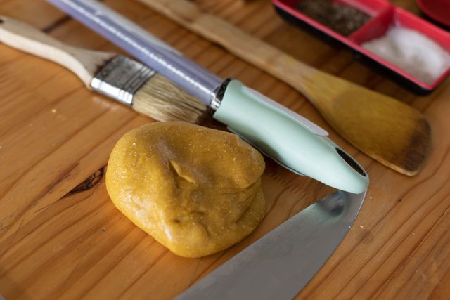 Piece of dough, brush, knife and stirring tool lying on a kitchen table. proffesional restaurant kitchen.