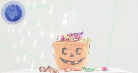 Halloween pumpkin bucket overflowing with colorful wrapped candies on white tabletop