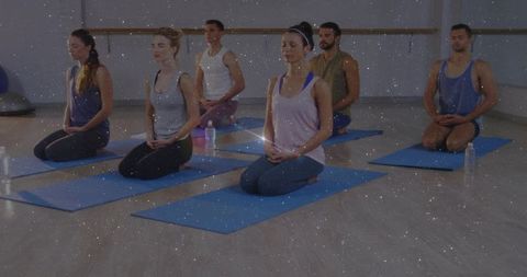 Seated meditation class kneeling on blue mats in yoga studio promoting calm and mindfulness