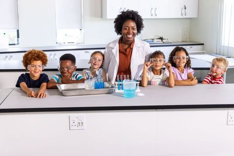African american teacher leading hands-on science experiment with smiling multiracial children