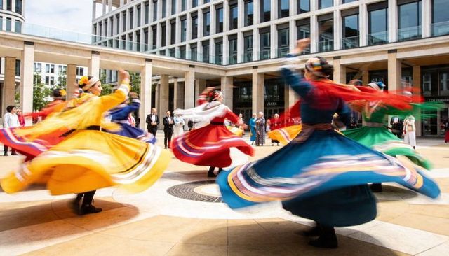 Spinning folk dancers wearing colorful skirts and embroidered headpieces in urban plaza