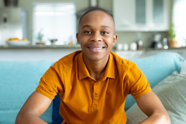 Portrait of african american male teenager smiling in living room - Download Free Stock Photos Pikwizard.com