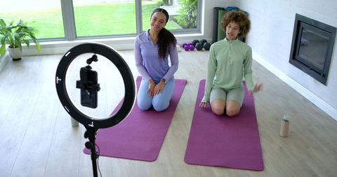 African american women filming home workout with ring light on purple mats, fitness vlog