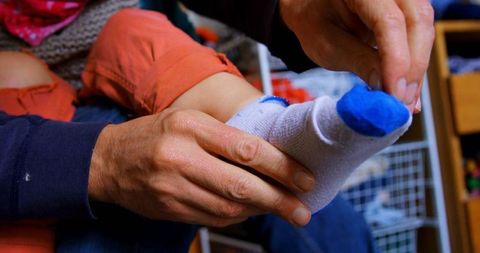 Father assisting son with socks at home