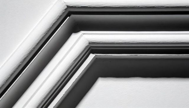 Layered crown molding close-up showing paint brush texture and shadow grooves in monochrome