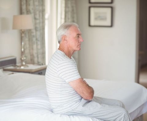 Senior Man Sitting on Bed Edge with Relaxed Posture in Cozy Bedroom