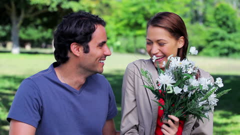 Couple Sharing Flowers with Laughter in Lush Countryside