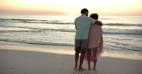 Couple embraced on beach watching romantic sunset