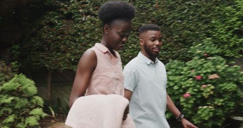 Young Couple Walking in Lush Garden Sharing a Joyful Moment