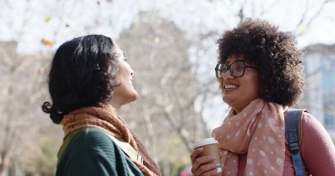 Asian and African-American Friends Laughing and Chatting on Campus Walkway with Coffee
