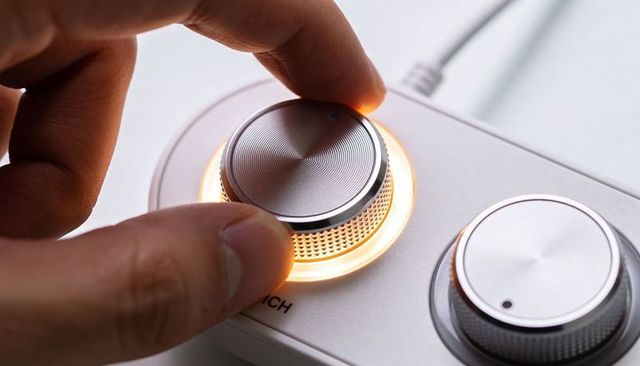 Precision illuminated rotary control dial with glowing led ring being adjusted by hand