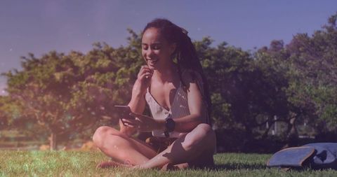 Smiling Woman Relaxing on Sunny Park Grass Using Smartphone