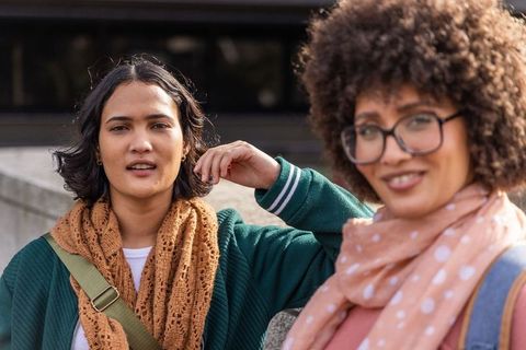 Urban friends chatting on plaza casual street style women wearing scarves and glasses