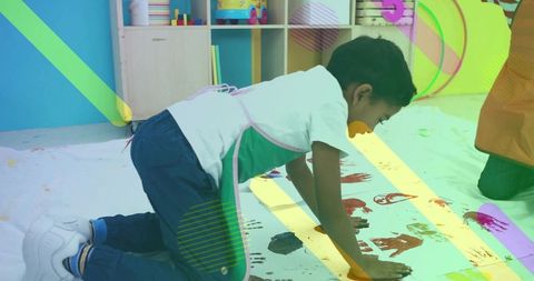 Preschool boy creating colorful handprint art on classroom floor paper roll