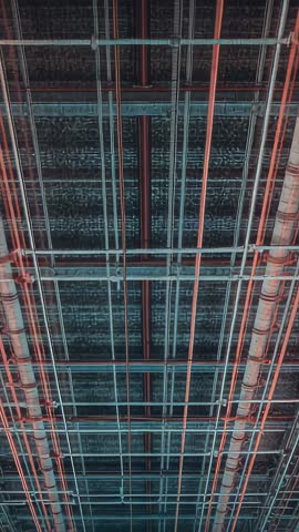 Vertical video tilting under-bridge ceiling grid with pipes, conduits and cable trays in teal-orange