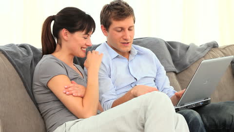 Couple Relaxing on Couch Using Laptop Together
