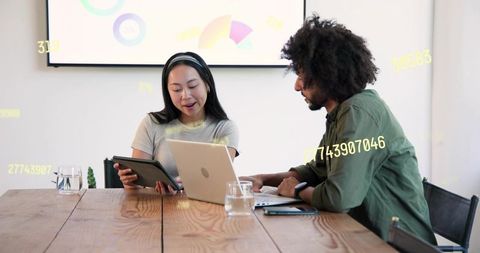 Young professionals collaborating over laptop and tablet reviewing analytics and charts
