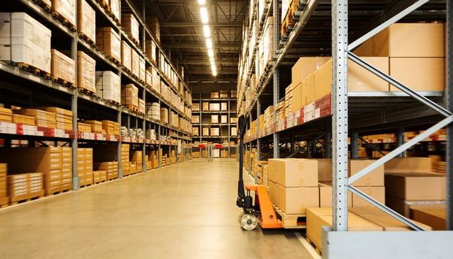 Wide warehouse aisle with pallet racking and orange pallet jack for logistics