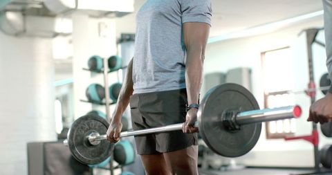 African American Men Lifting Loaded Barbell While Partner Spotting Strength Training Gym