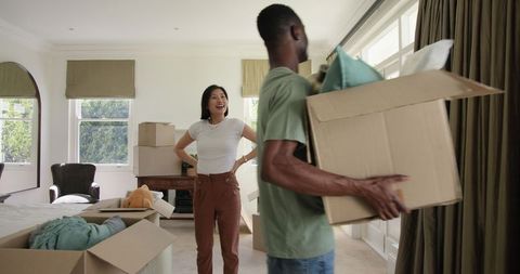Joyful couple unpacking in sunlit bedroom during move