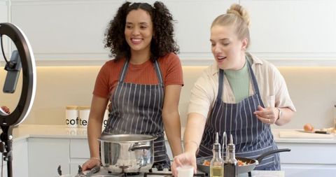 Diverse female friends cooking in kitchen with ring light