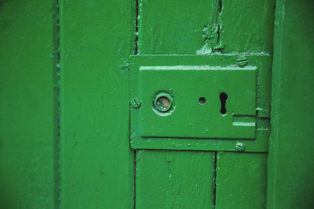 Close-up of a vintage green door lock, perfect for use in themes related to security, history, or rustic decor. Ideal for backgrounds, design projects, or illustrating concepts of protection and antiquity.