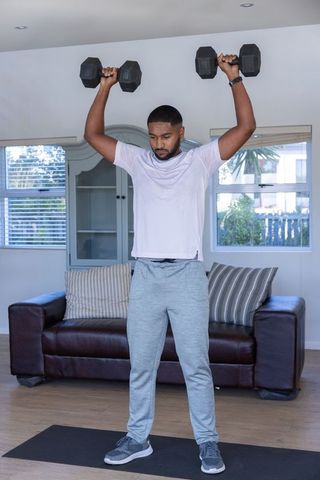 Man Lifting Dumbbells at Home in Modern Living Room for Strength Training