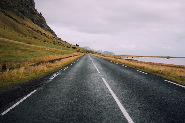 Long empty road stretches through remote countryside, ideal for showcasing the beauty of nature and the sense of adventure. Perfect for use in travel blogs, adventure-themed websites, promotional materials for road trips, and backgrounds for inspirational quotes.